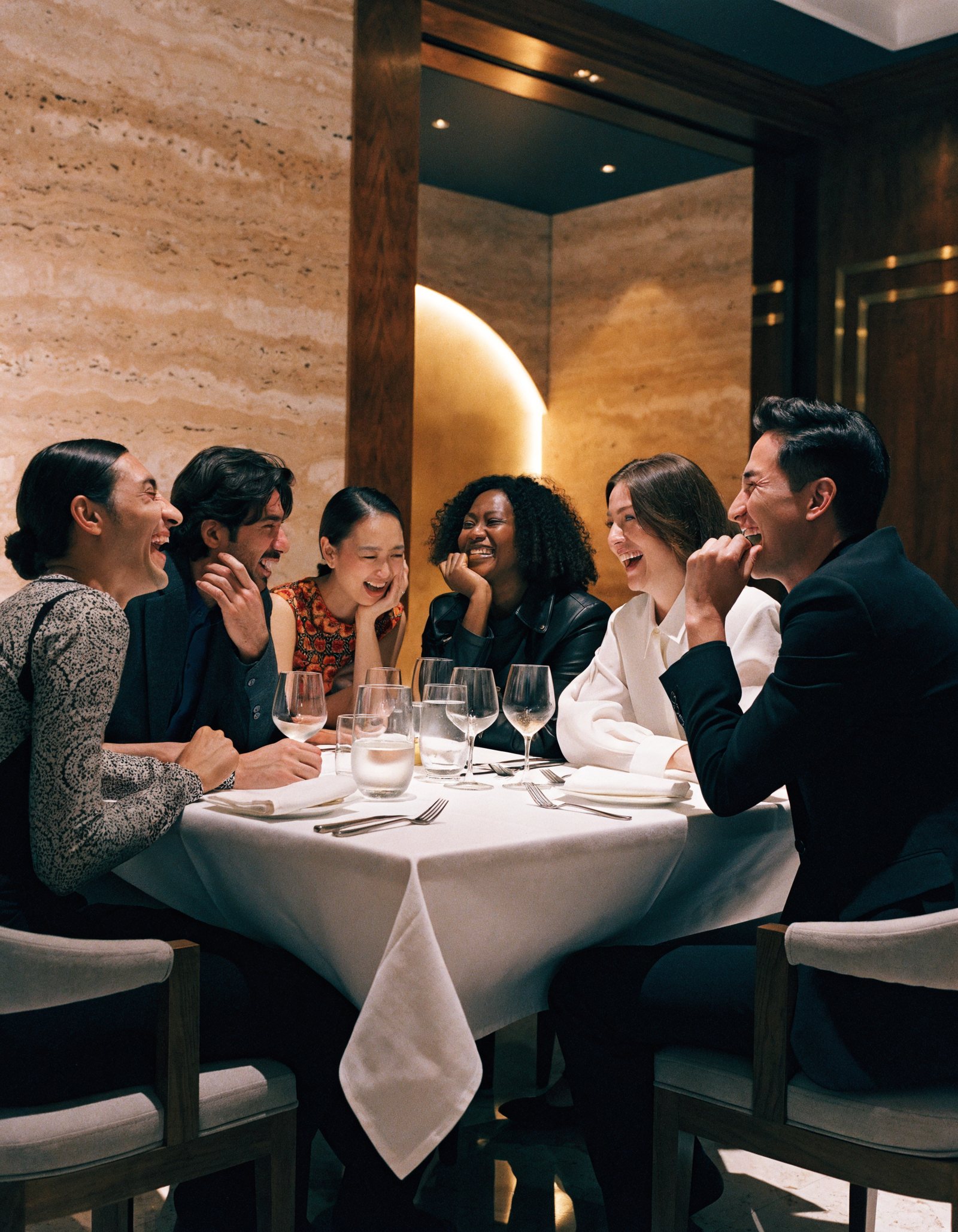 Six people laughing around a dinner table